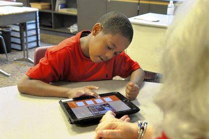 Marlene Berncic helps a student work on an iPad during a second- to fourth-grade class at Pace school in Churchill. Robin Rombach/Post-Gazette