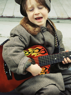Young boy playing with child-size guitar