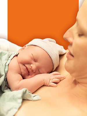 mother holding newborn in front of orange background