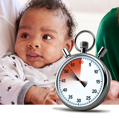 Black infant in mothers arms with ticking stopwatch in foreground